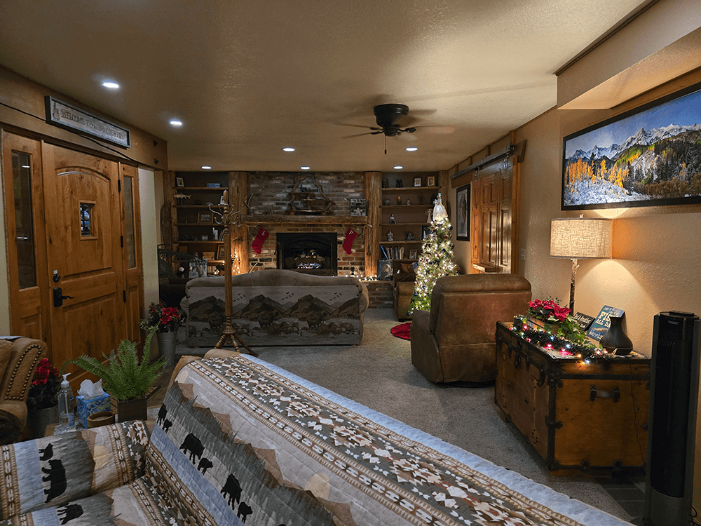 Cozy living room decorated for the holidays with a tree, a fireplace, and rustic furnishings.